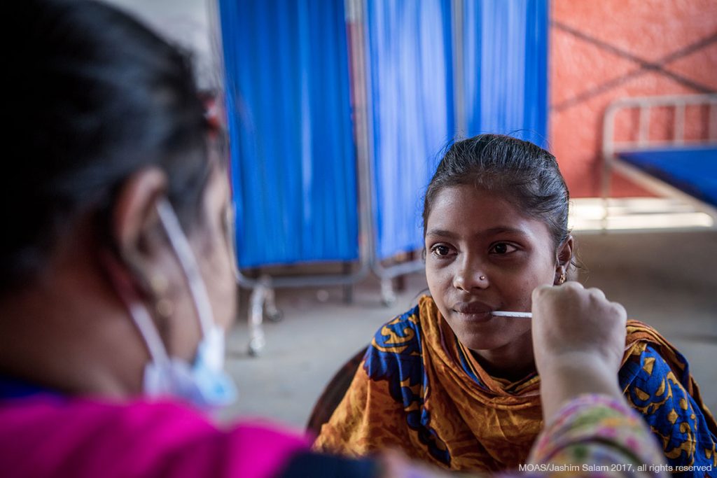 A young girl has her temperature taken by a MOAS nurse in Shamlapur Aid Station.