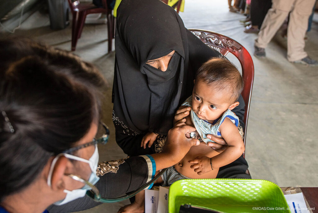 A MOAS doctor checks over a young rohingya child who had been brought into the MOAS Aid Station by his worried mother.