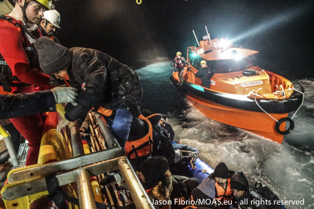 Helped by MOAS crew, a child climbs onto the Responder from a rubber boat in the Aegean Sea.