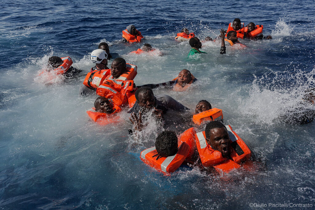 A MOAS rescue swimmer attempts to help several people who had fallen overboard from a rubber boat in the Central Mediterranean.